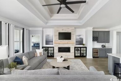 Living area featuring wine cooler, a raised ceiling, crown molding, wood finished floors, and a ceiling fan