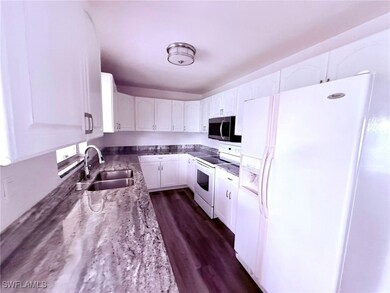 Kitchen featuring white appliances, a sink, white
