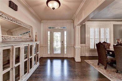 Entrance foyer with a decorative wall, plenty of natural light, dark wood-style floors, crown molding, and wainscoting