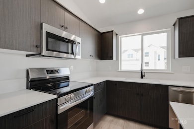 Kitchen with appliances with stainless steel finishes, modern cabinets, light wood finished floors, dark brown cabinets, and recessed lighting