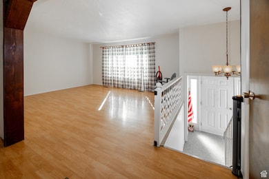 Spare room with a chandelier and light wood finished floors