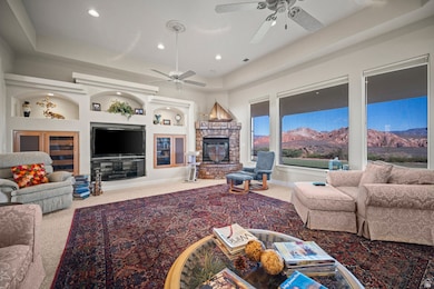 Living area with a raised ceiling, light carpet, built in features, a fireplace, and recessed lighting