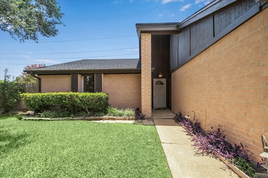A covered front entry and neatly trimmed hedges cr
