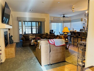 Living room featuring a fireplace, tile patterned flooring, and ceiling fan