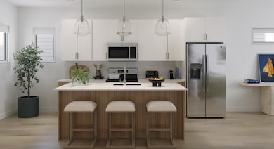 Kitchen with stainless steel appliances, light wood-type flooring, pendant lighting, decorative backsplash, and a kitchen island with sink