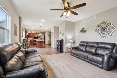 Living area with ceiling fan, light wood-type flooring, light carpet, and recessed lighting