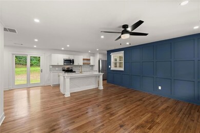 Unfurnished living room featuring a decorative wall, a sink, a ceiling fan, light wood-type flooring, and recessed lighting