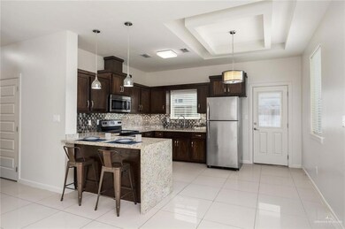 Kitchen featuring a kitchen bar, hanging light fixtures, appliances with stainless steel finishes, kitchen peninsula, and a raised ceiling