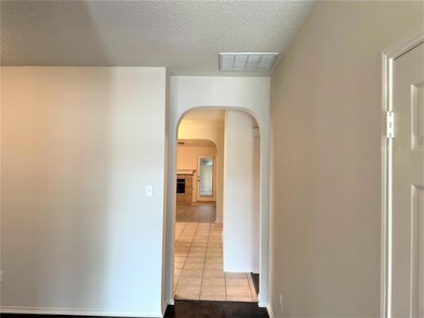 Hallway featuring tile patterned floors and a textured ceiling