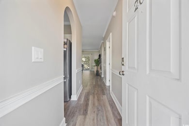 Hallway featuring light wood-style floors, arched walkways, and ornamental molding