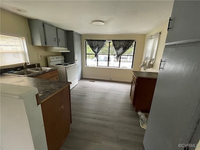 Kitchen with white electric stove, a sink, dark co
