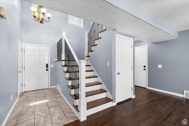 Foyer with a textured ceiling, stairway, and a chandelier