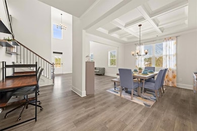Dining area with a chandelier, wood finished floors, stairs, beam ceiling, and coffered ceiling