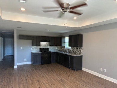 Kitchen featuring tasteful backsplash, black appliances, dark wood-style flooring, a raised ceiling, and recessed lighting