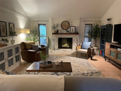 Living room featuring vaulted ceiling, light tile patterned floors, a fireplace, and crown molding