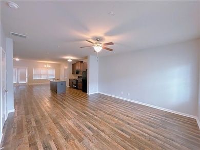 Unfurnished living room with baseboards, wood finished floors, a ceiling fan, and a chandelier