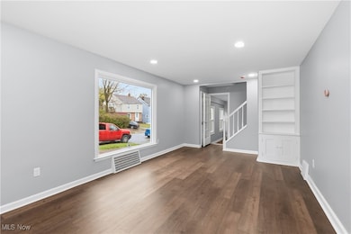 Spare room featuring built in features, dark wood finished floors, stairway, and recessed lighting