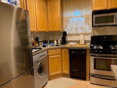 Kitchen featuring stainless steel appliances, light countertops, washer / clothes dryer, and light tile patterned flooring