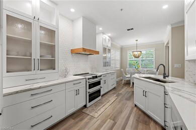 Kitchen with sink, white cabinetry, custom range h