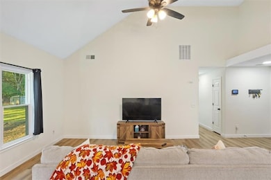 Living area with light wood finished floors, high vaulted ceiling, and a ceiling fan