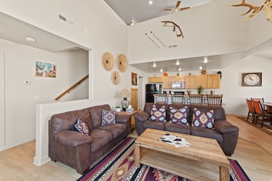Living room featuring ceiling fan, light wood-style floors, and a high ceiling