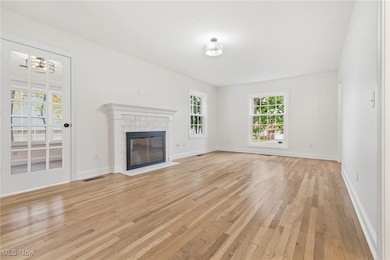 Unfurnished living room featuring light wood floors and a tiled fireplace