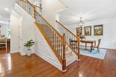 Stairs featuring a decorative wall, a chandelier, wood-type flooring, recessed lighting, and wainscoting