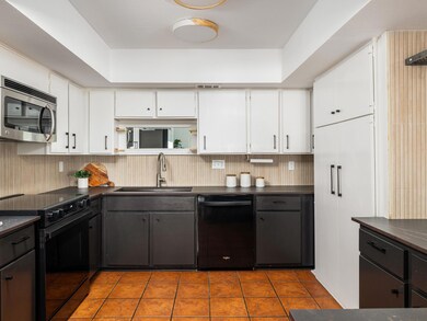 Kitchen featuring white cabinetry, a sink, dark c