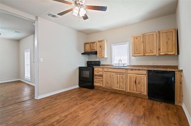 Kitchen featuring wood-type flooring, sink, black appliances, and ceiling fan