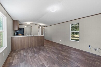Kitchen featuring light countertops, a peninsula, dark wood-style floors, lofted ceiling, and brown cabinets