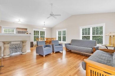 Living room with light wood finished floors, lofted ceiling, and ceiling fan