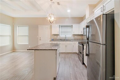 Kitchen with stainless steel appliances, decorative light fixtures, light hardwood / wood-style flooring, a center island, and white cabinetry