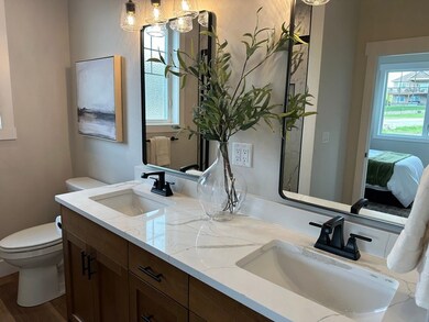 Bathroom featuring double vanity, ensuite bath, a chandelier, and dark wood-style floors