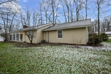 Rear of home featuring a sunroom on treed lot.