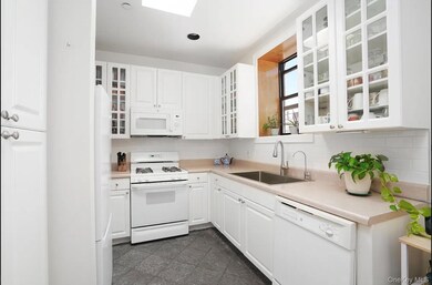 Kitchen with white appliances, white cabinets, light countertops, decorative backsplash, and glass insert cabinets