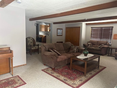 Living room with beamed ceiling, carpet floors, an