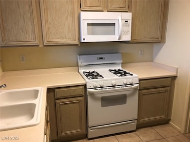 Kitchen featuring white appliances, a sink, light