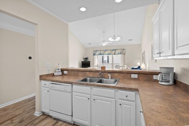 Kitchen featuring white dishwasher, ceiling fan, dark countertops, white cabinetry, and a peninsula
