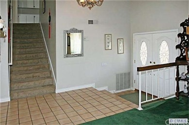 Double Entry Doors Open to Tiled Foyer and Soaring