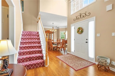 Entrance foyer with stairway, light wood-style flooring, and a high ceiling
