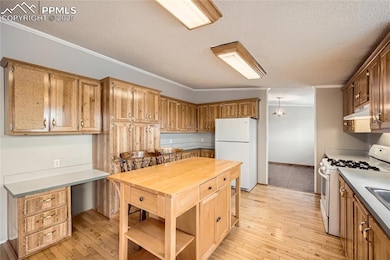 Kitchen featuring white appliances, light wood fin