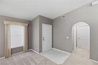 Spare room featuring light colored carpet, light tile patterned flooring, and arched walkways