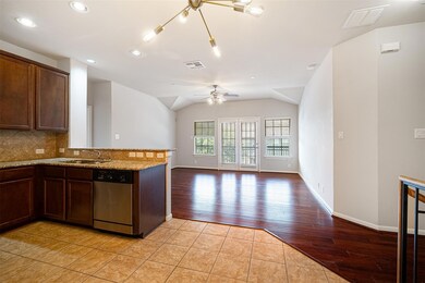 Kitchen featuring decorative backsplash, dishwasher, light stone countertops, open floor plan, and dark brown cabinets