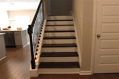 Staircase with wood finished floors and crown molding