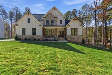Modern inspired farmhouse with a porch, board and batten siding, a front lawn, and stone siding