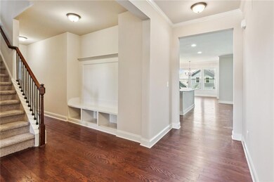Foyer featuring dark wood-style flooring, baseboards, stairway, and crown molding