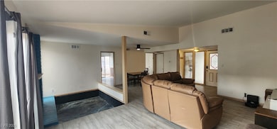 Living area featuring vaulted ceiling, light wood-type flooring, and a ceiling fan