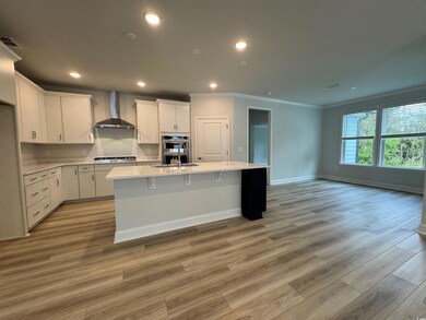 Kitchen featuring an island with sink, wall chimne