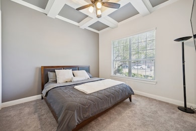 This front downstairs bedroom is an optional office with ensuite full bath and walk-in closet.  It features coffered ceiling, carpet floors, and a ceiling fan