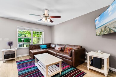 Living room with ceiling fan and light wood-type f